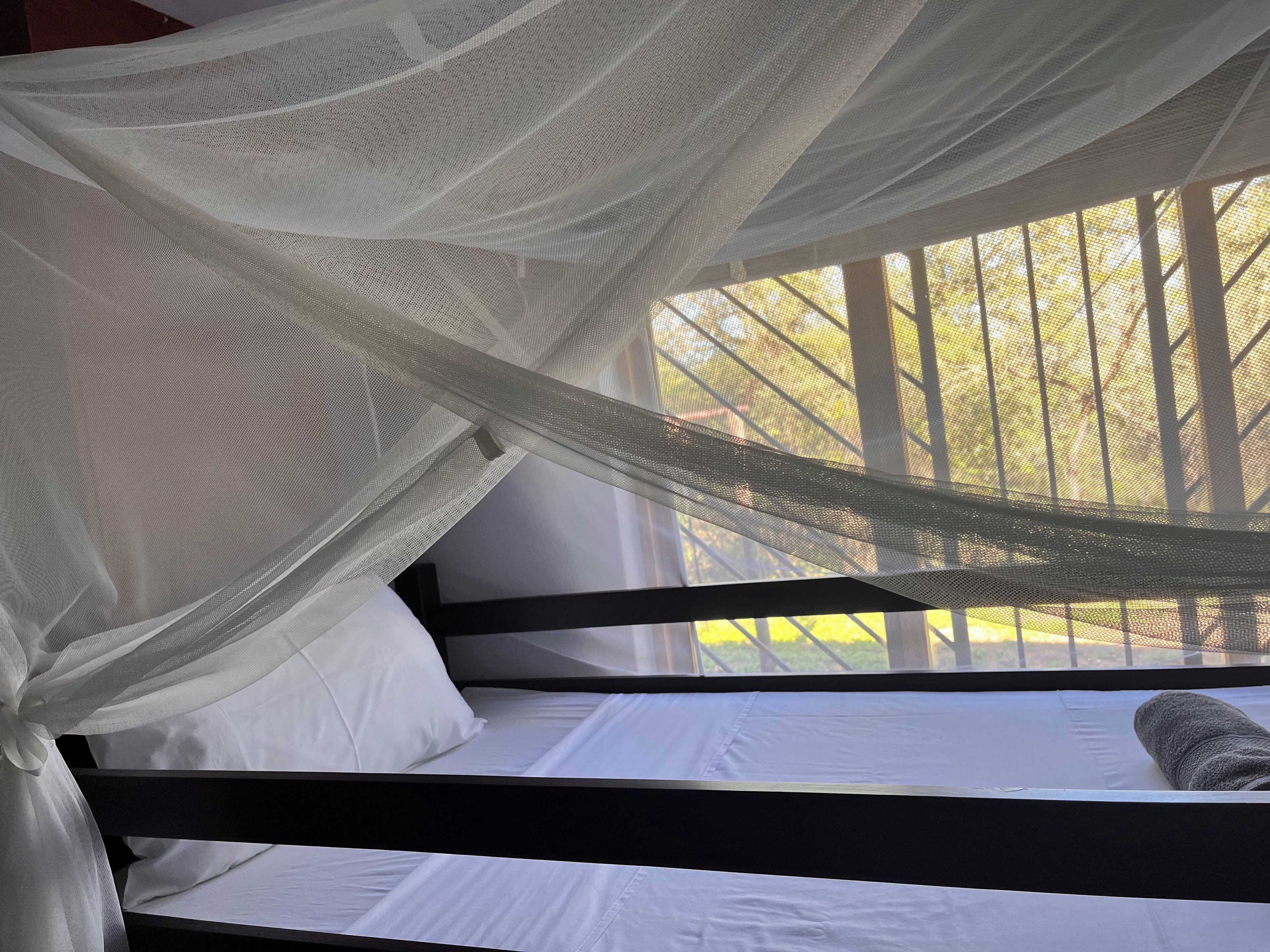 Een bed met witte lakens en een klamboe.