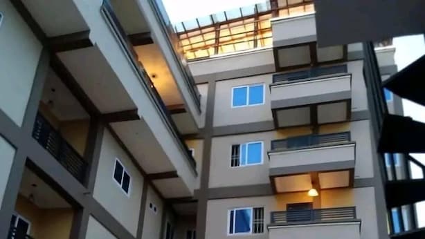 A multi-story residential building with balconies, windows, and a gated entrance. - SmileVew Apartments (Accra)