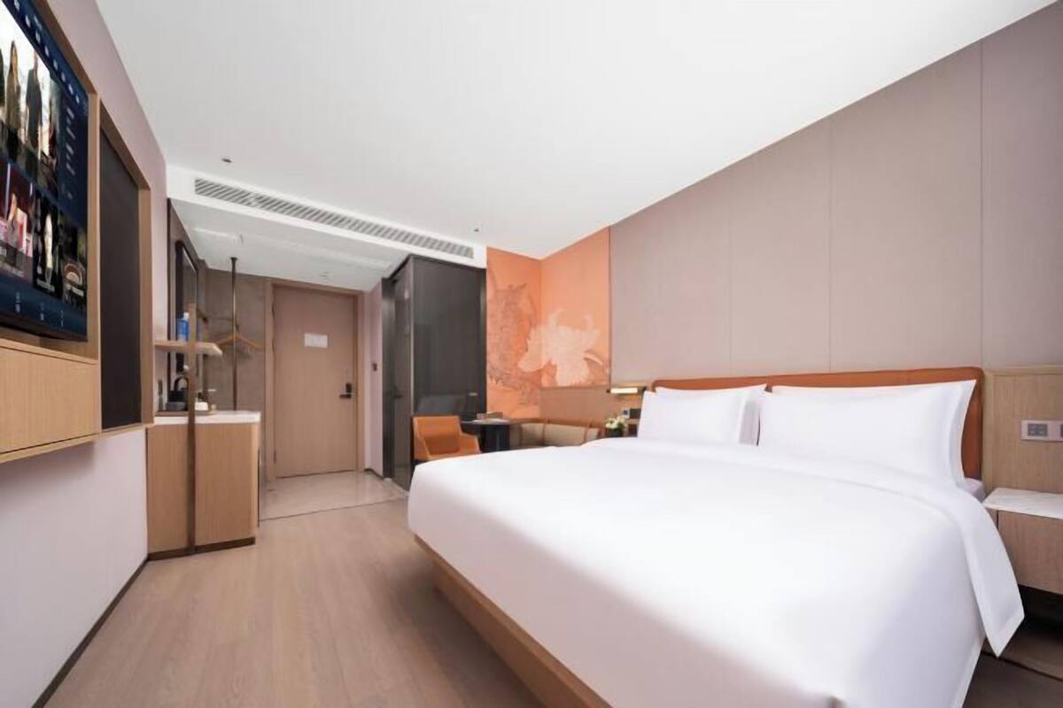 Une chambre d’hôtel moderne, dotée d’un grand lit, d’un bureau et d’une télévision.