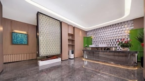A modern hotel lobby with a reception desk, a patterned wall, and a large abstract painting. - Xingye International Hotel (Yiwu International Trade City) (Yiwu)