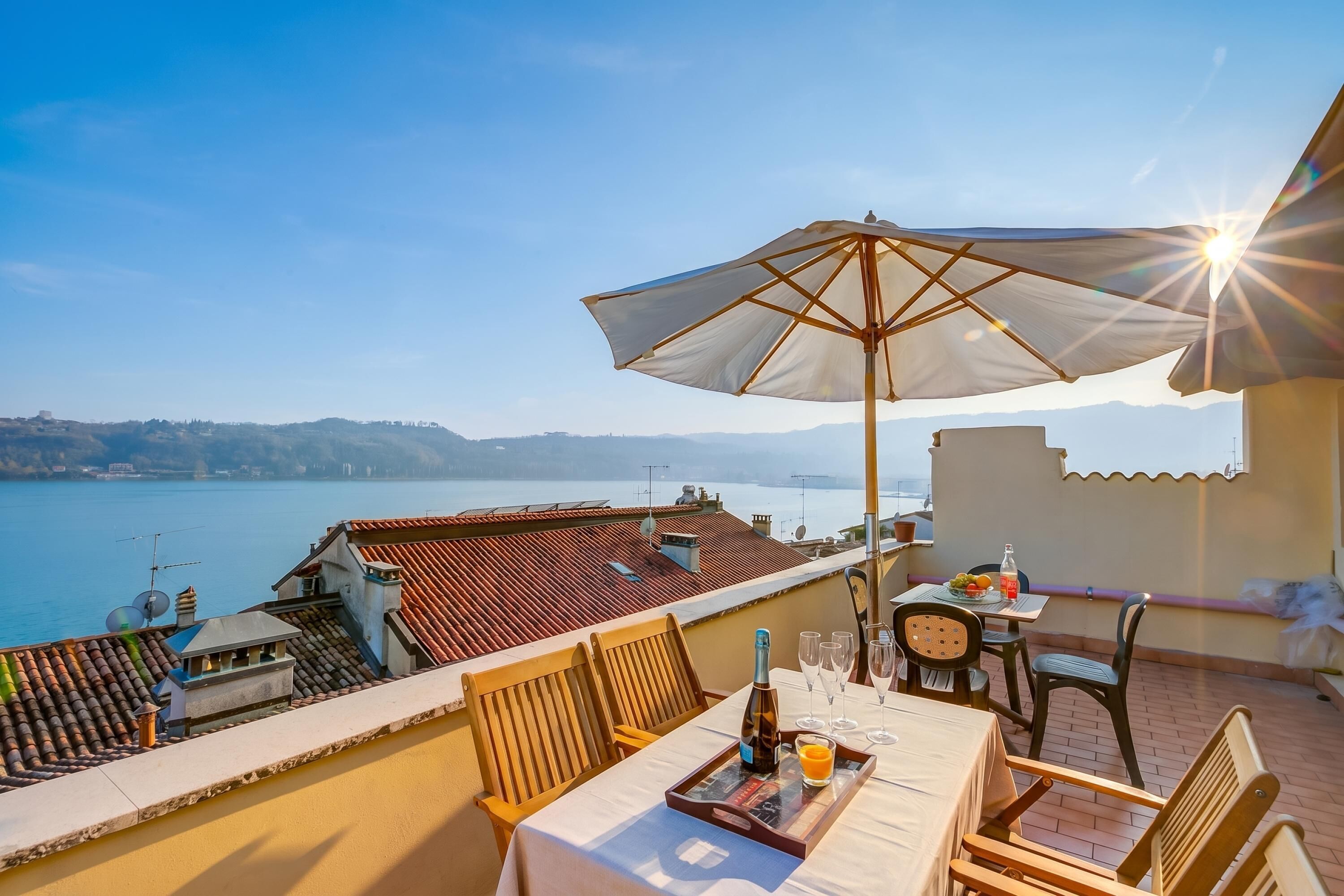 A terrace with a table set for two, a bottle, glasses, and a tray with a drink.