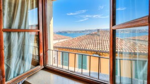 A balcony with a view of terracotta-roofed buildings and a body of water. - Laetitia Salo-historic Center Near Lake (Salò)