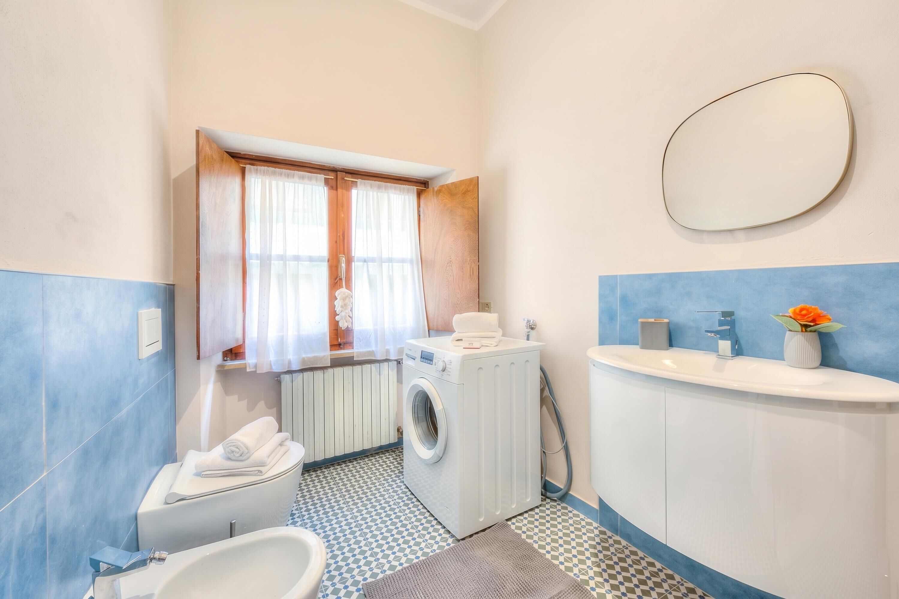 Een kleine badkamer met een wasmachine, toilet, wastafel en een spiegel.