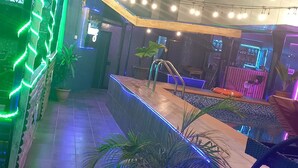 A pool area with a tiled floor, potted plants, and a seating area with a bench. - Marriot Airport Hotels (Lagos)