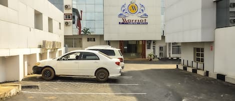 Un hotel Marriott cerca del aeropuerto, con fachada moderna, coches aparcados y una zona de entrada pavimentada.