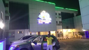 A Marriott hotel with a prominent sign, a parked car, and a person standing by the entrance. - Marriot Airport Hotels (Lagos)