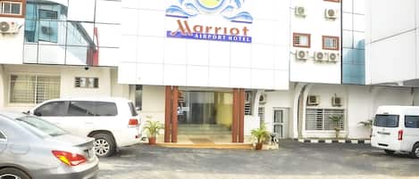 A Marriott Airport Hotel with a modern facade, air conditioning units, and a paved entrance area.
