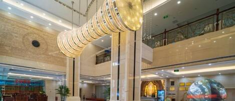 Un vestíbulo amplio con una columna central, una mesa de recepción y un globo decorativo.