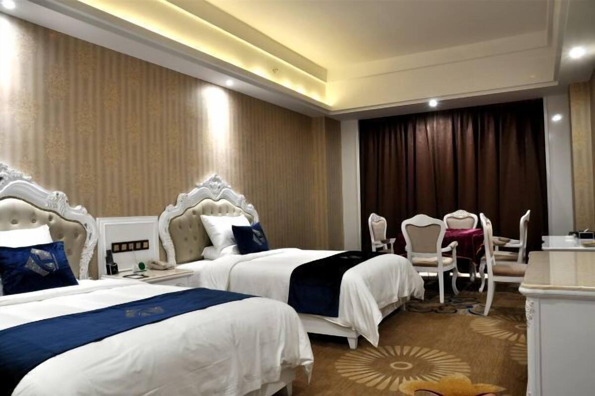 Een hotelkamer met twee bedden, een bureau en een stoel.