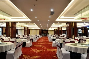 A banquet hall with round tables, white chairs, and a red carpet.