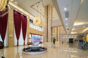 Un hall espacioso con una fuente central, una recepción y una escalera que conduce a los pisos superiores.