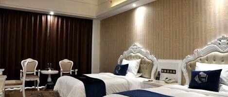 A hotel room with two beds, a small table with chairs, and a large window with curtains.