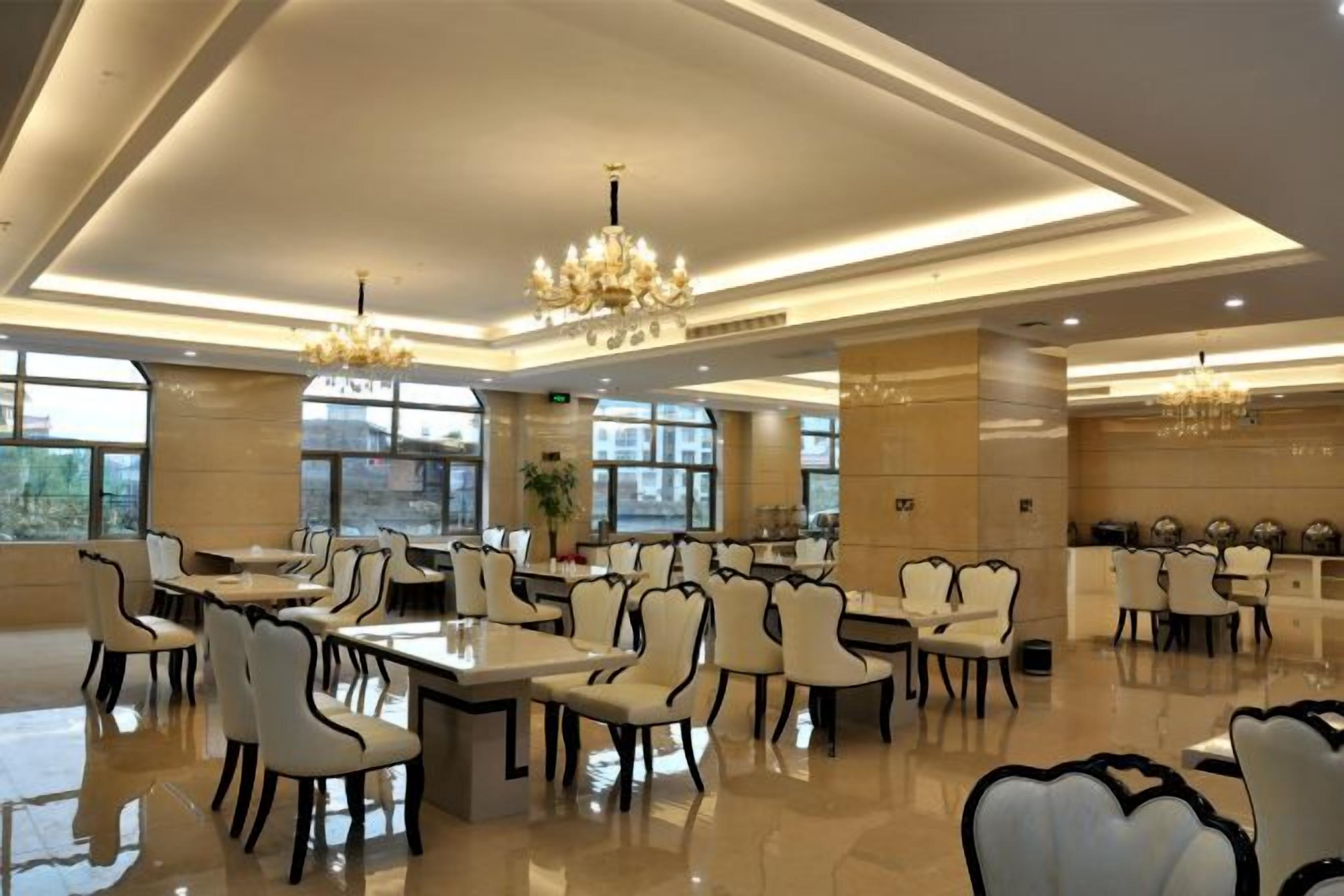 A spacious dining area with high ceilings, chandeliers, and a modern design.