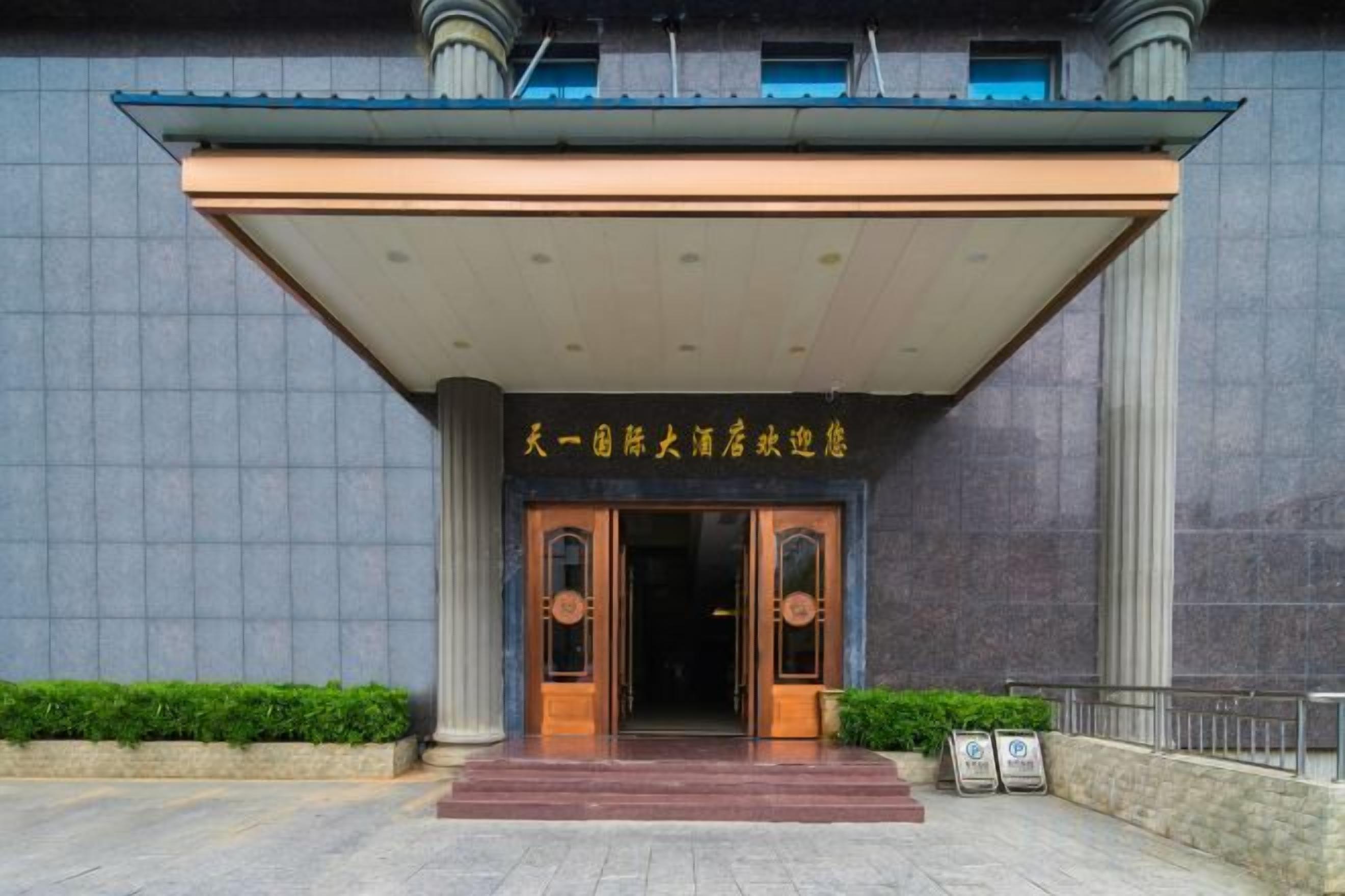 A hotel entrance with a covered walkway, double doors, and a sign above the doors.