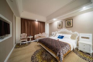 A hotel room with a large bed, two chairs, a small table, and a television. - Tianyi International Hotel (Jianghua)