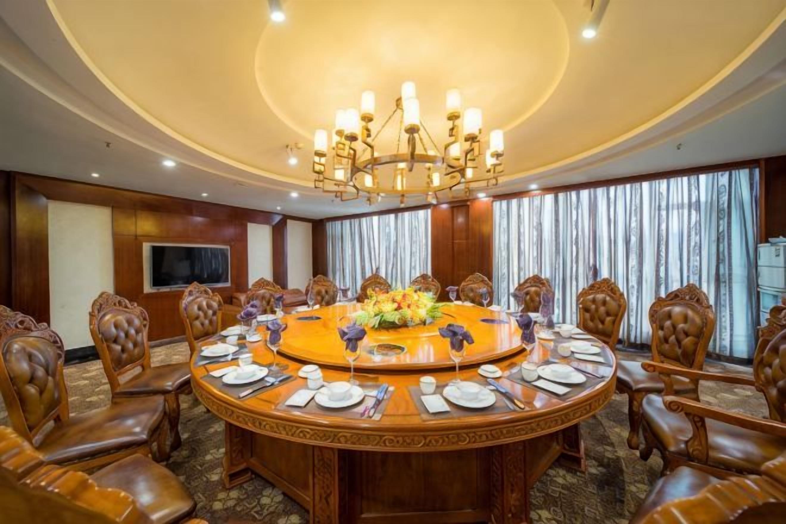 A conference room with a round table, chairs, and a chandelier.