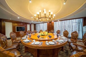 Un salón de conferencias con una mesa redonda, sillas y una araña.