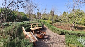 A garden with a wooden bench, a picnic table, and a fire pit. - Luxury 3 BR Villa in Marrakesh With Private Pool, Marrakesh Villa 1000 (Ourika)