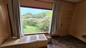 A room with a window overlooking a garden, a wooden bench, and a door with a shutter. - Luxury 3 BR Villa in Marrakesh With Private Pool, Marrakesh Villa 1000 (Ourika)