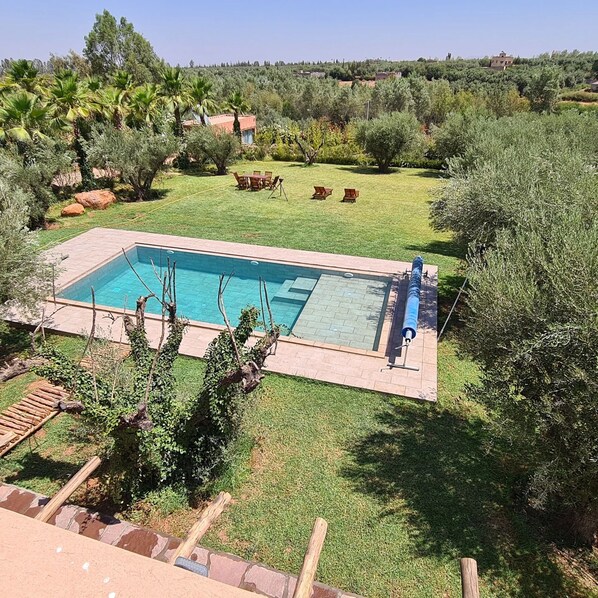 A rectangular swimming pool with a tiled deck, surrounded by a grassy lawn and various trees. - Luxury 3 BR Villa in Marrakesh With Private Pool, Marrakesh Villa 1000 (Ourika)
