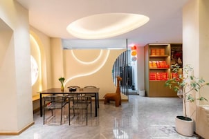 A modern interior with a dining area, a staircase, and a bookshelf.