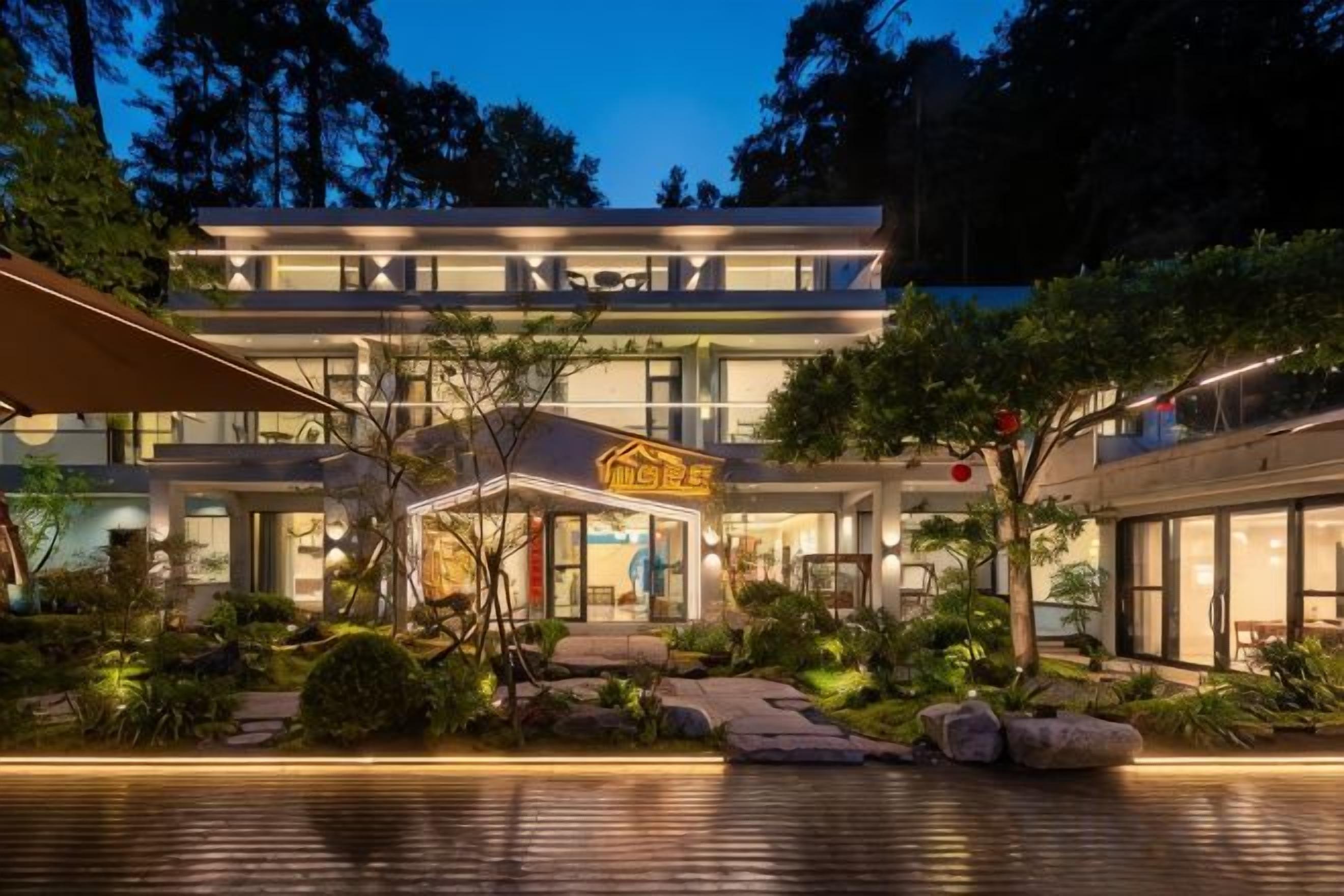 Un hotel moderno con una estructura de dos pisos, una entrada bien iluminada y un jardín ajardinado.