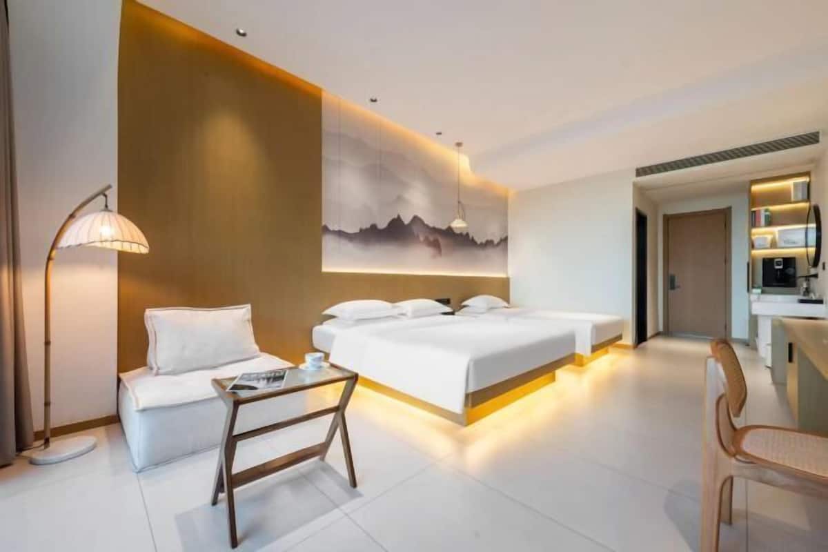 A modern hotel room with a large bed, bedside tables, a desk, and a chair.