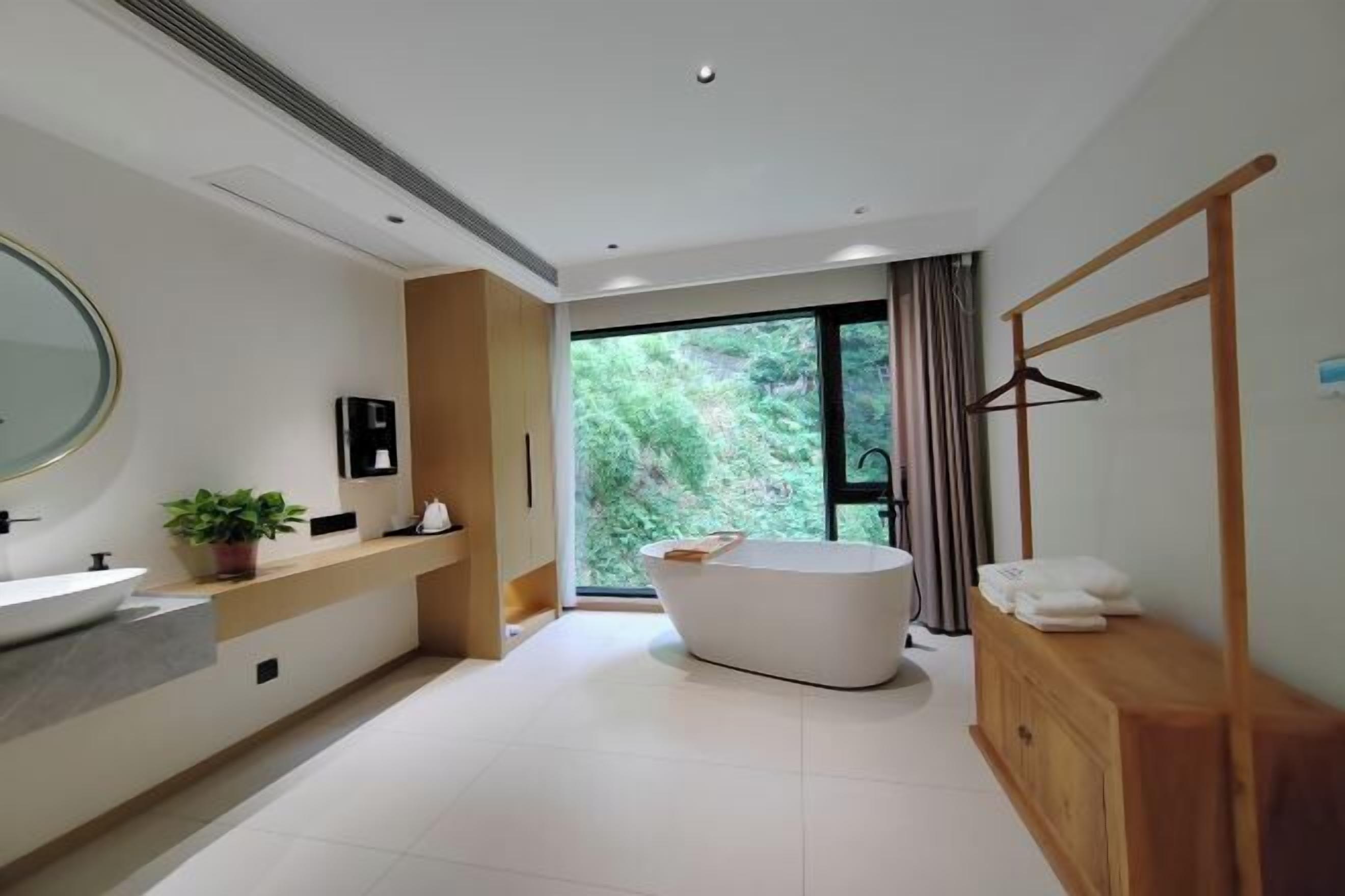 Un baño moderno con una bañera independiente, un espejo grande y un tocador de madera.