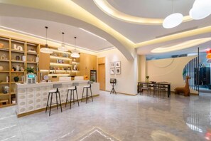 Uma área de bar moderna com teto curvo, banquetas e iluminação pendente.