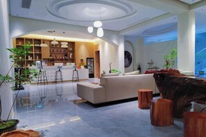 En moderne hotellobby med receptionsdisk, siddeområde og en stor træskulptur.