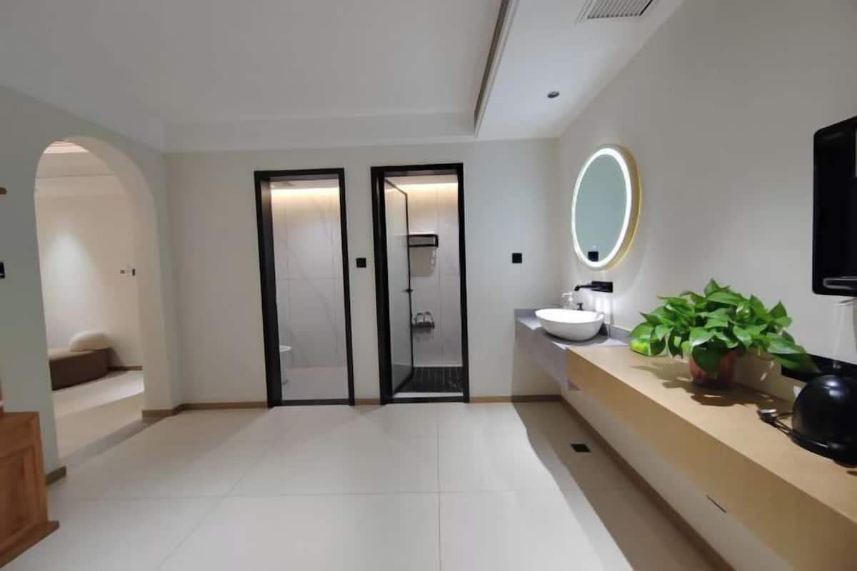 A modern bathroom with a large mirror, a sink, and a shower.