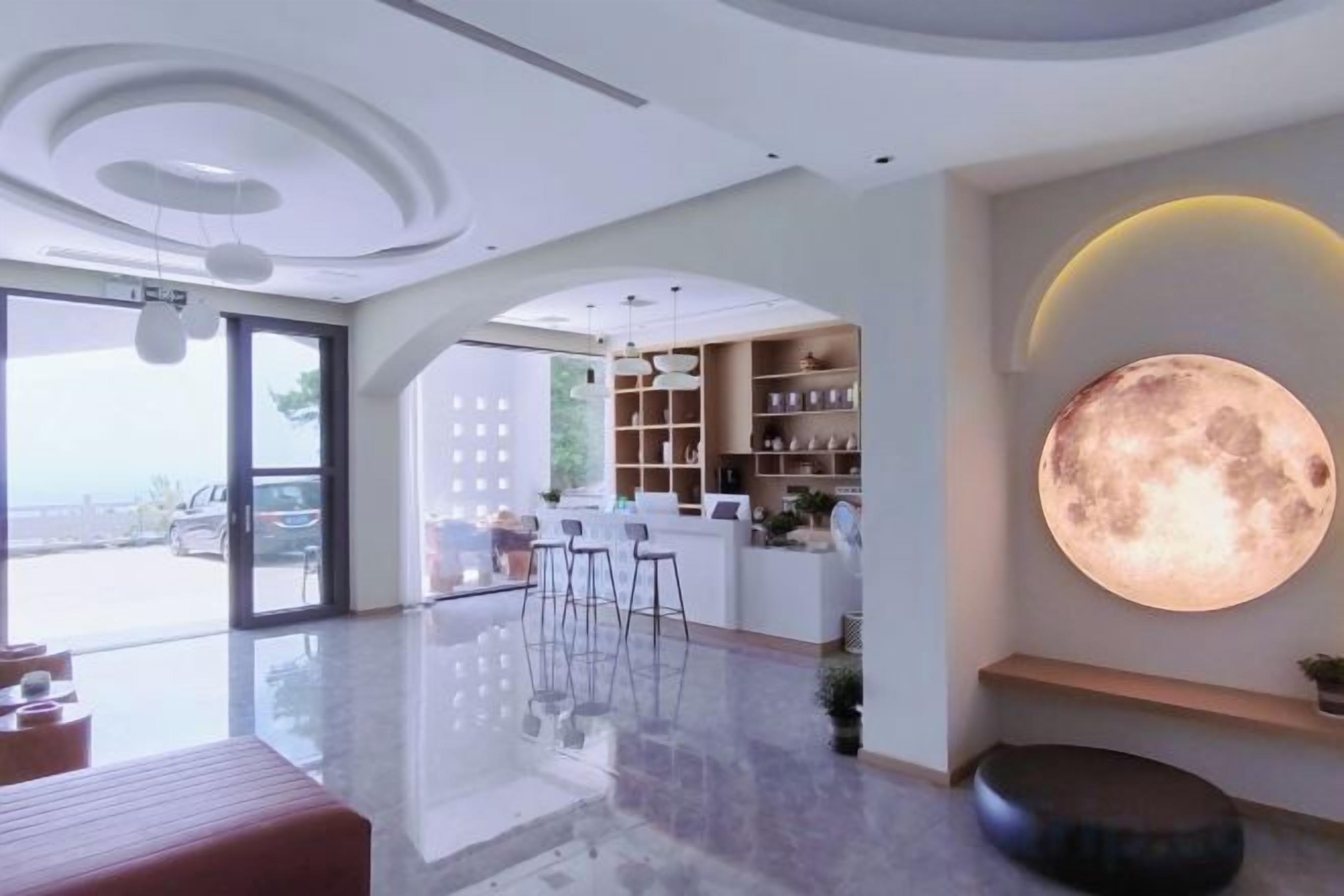 A modern interior with a large moon-like wall feature, a bar area, and a seating space.