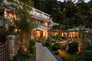A modern two-story house with a well-lit garden pathway, surrounded by lush greenery. - Mountain and Courtyard Homestay (Hengyang)