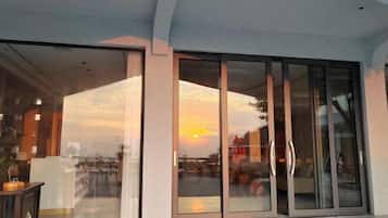 A modern building with large glass doors and windows, reflecting a sunset.