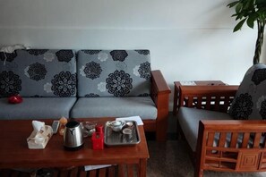 A living room with a sofa, a wooden coffee table, and a chair. - Haozhujia Hotel (Yangshuo)