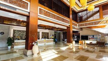 A spacious lobby with high ceilings, a reception desk, and a check-in counter.