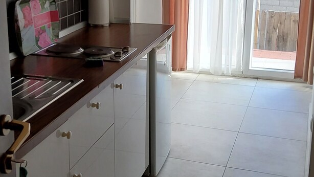A kitchen with white cabinets, a wooden countertop, and a window with curtains. - Appealing Apartment 8 Sleeps 3 Guests (Split)