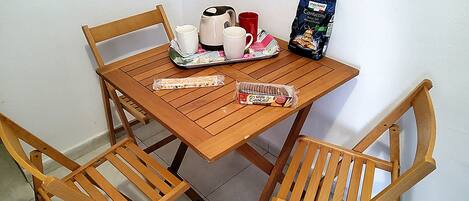 Et træbord med en bakke, der indeholder en kagedåse, en kaffekande og en rød kop.