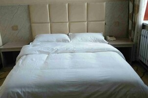Una cama con cabecera acolchada, una mesita de noche y un velador.