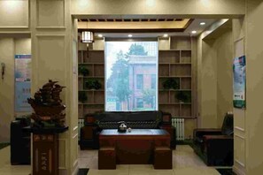 Un área de recepción con un sofá, una mesa y un pilar decorativo.