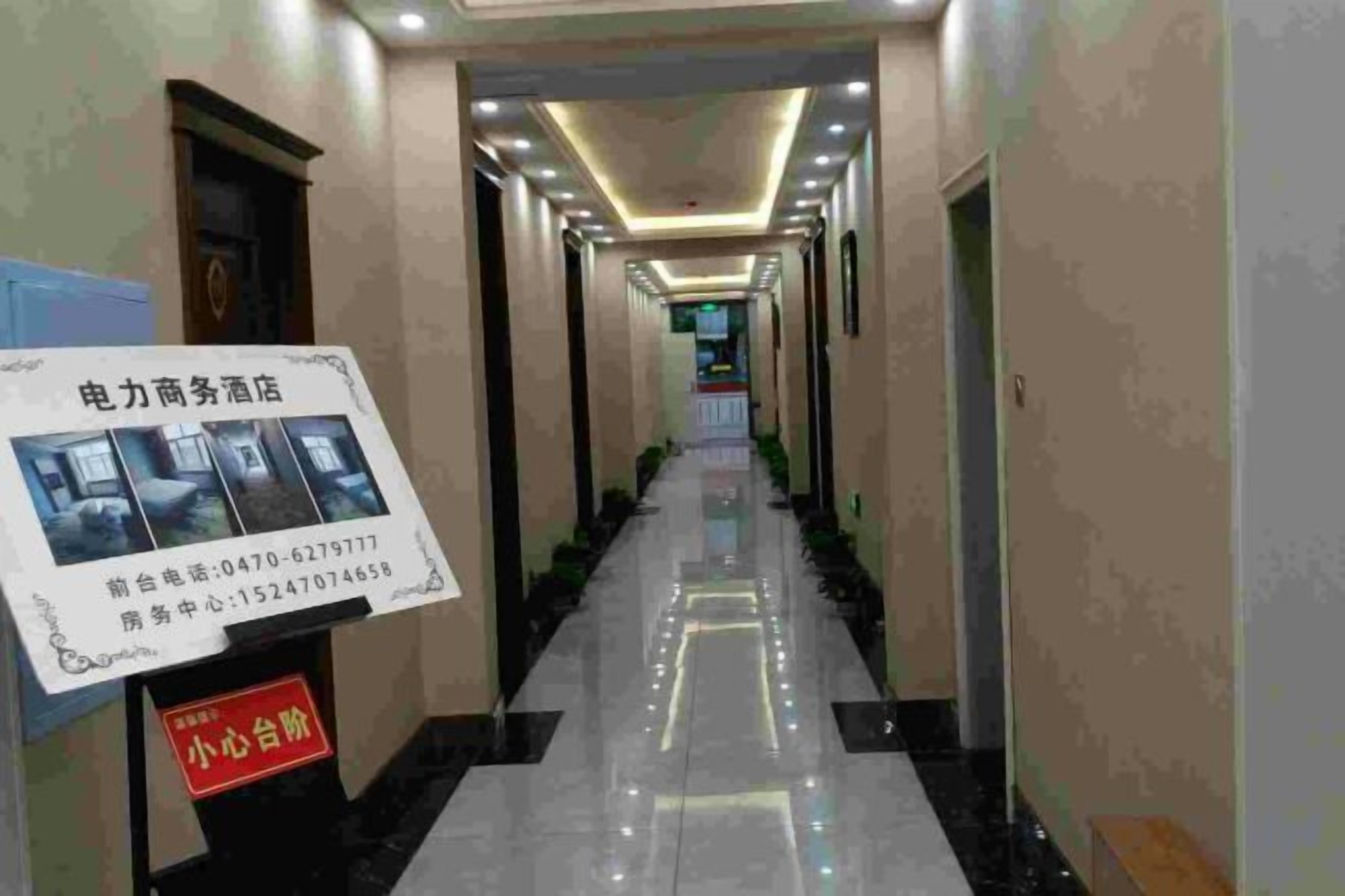 A hotel corridor with a signboard, a reception desk, and a clean, tiled floor.