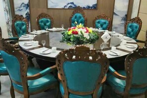 Una mesa redonda de comedor con sillas, un centro de mesa y un cuadro en la pared.