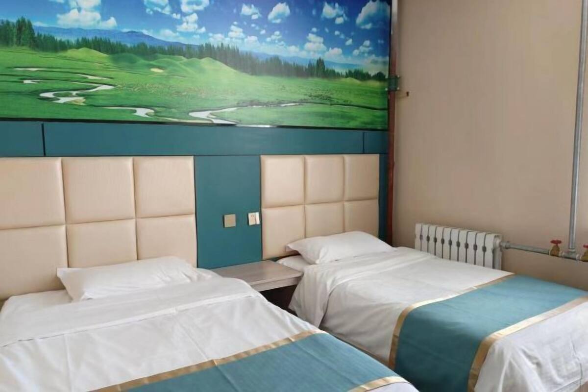 A hotel room with two beds, a mural of a golf course, and a radiator.