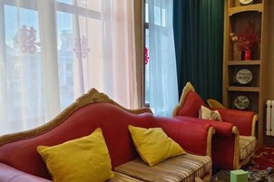Un sofá rojo con cojines amarillos, un cojín a rayas y una mesita con una caja verde.