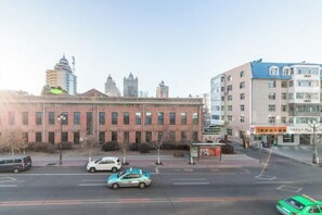 Vista de la calle con un edificio de ladrillo rojo, una parada de autobús y edificios modernos altos al fondo.