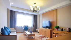 Uma sala de estar moderna com sofá, mesa de centro, televisão e área de refeições.