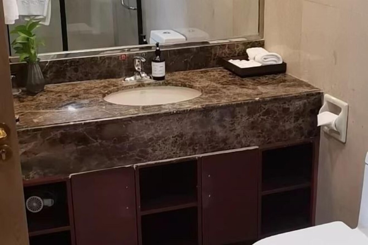 A bathroom with a marble sink, a bottle of shampoo, and a towel rack.