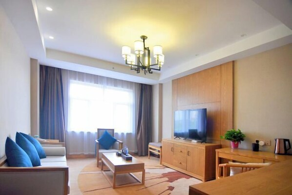 A modern living room with a sofa, coffee table, TV, and wooden cabinets. - Weishan Lake Hotel (Jining)