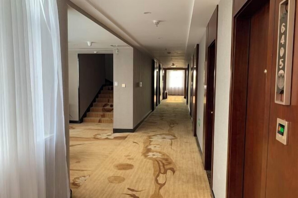 A hotel hallway with a carpeted floor, wooden doors, and a staircase leading to another room.