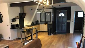 A modern kitchen with a bar area, wooden flooring, and a large window.